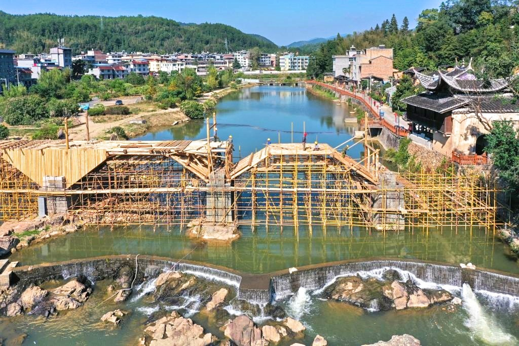 A drone photo taken on Oct. 18, 2023 shows workers working on the restoration of the Wan'an Bridge, a wooden arch bridge, in Changqiao Township of Pingnan County, southeast China's Fujian Province.(Photo by Wang Zhiling/Xinhua)